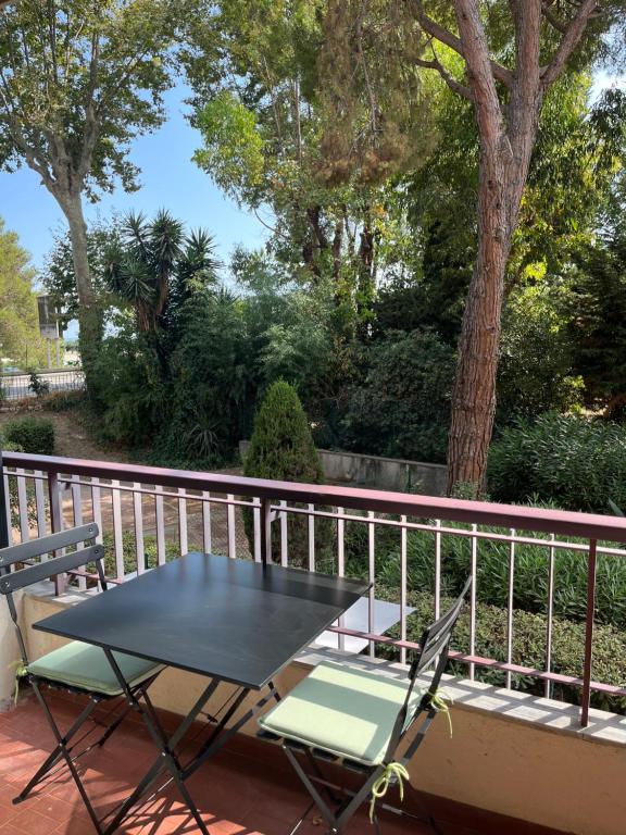 une table noire et des chaises sur un balcon dans l'établissement Charmant studio à 5 min de la mer, à Cagnes-sur-Mer