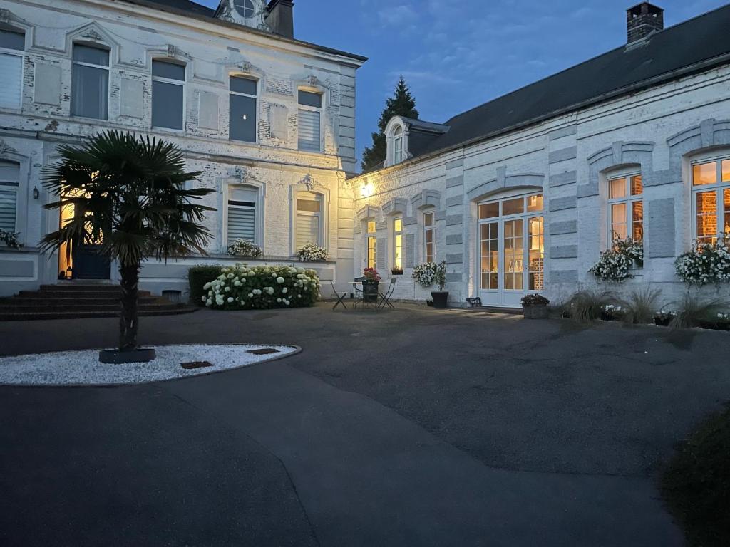 un grand bâtiment blanc avec un palmier devant dans l'établissement Le Clos, à Hucqueliers