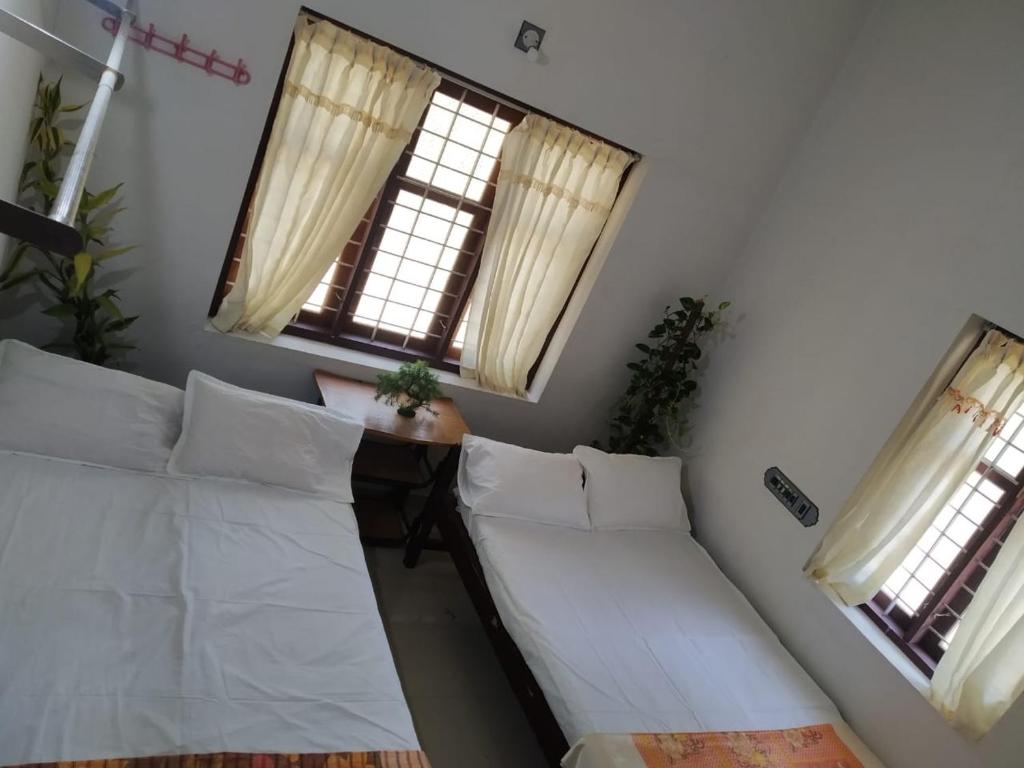 a room with two beds and two windows at Avani Home Stay in Iritti