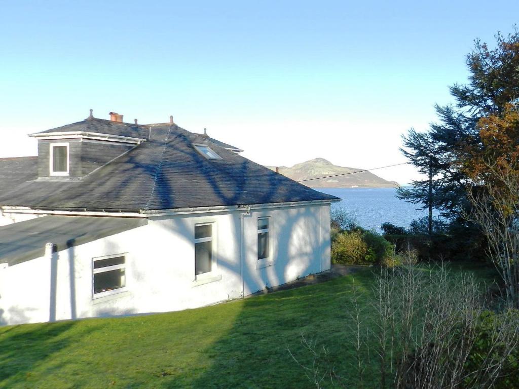 ein weißes Haus, das auf einem Grasfeld steht in der Unterkunft Ardbeag in Whiting Bay