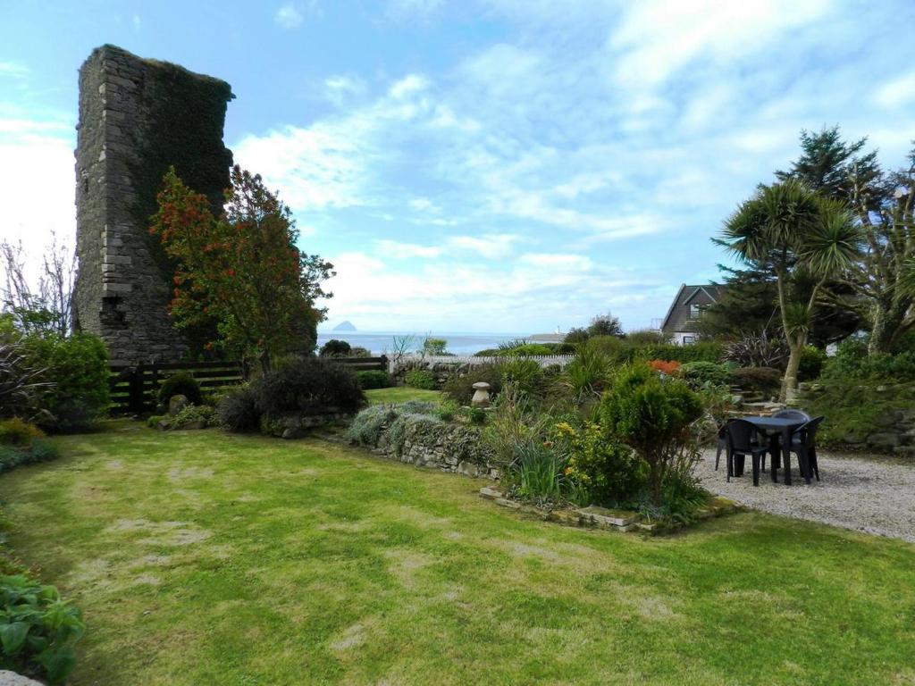an old stone house with a garden and a table at Castleside Croft in Kildonan