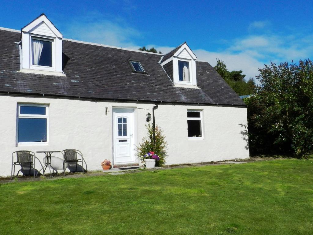 a white house with a lawn in front of it at Mont Stewart Cottage in Whiting Bay