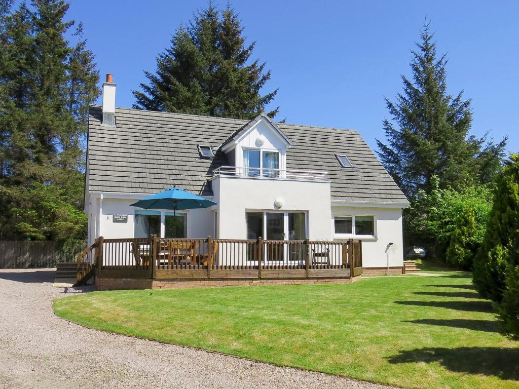 a house with a deck with an umbrella at Glen Rosa Lodge in Brodick