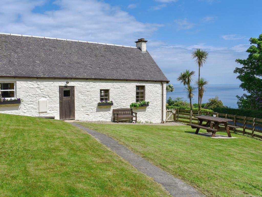 a white building with a picnic table and a bench at Woodlea Cottage 2 in Dippin