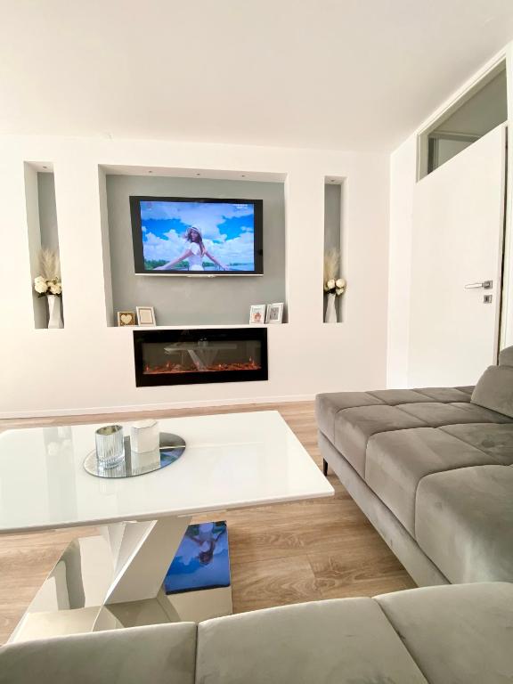 a living room with a couch and a tv on a wall at Black & White Hideaway with garage in Ljubljana
