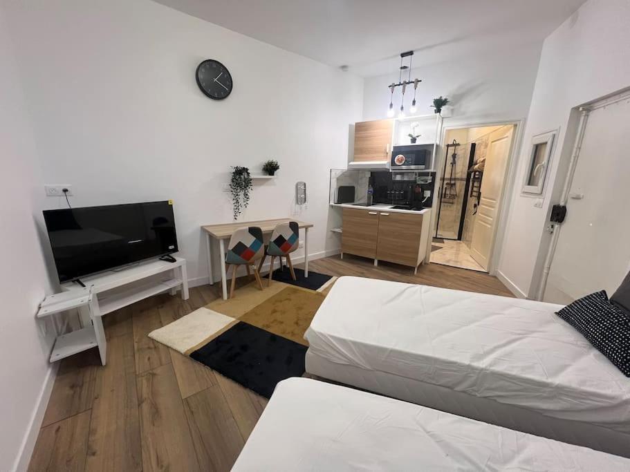 ein weißes Wohnzimmer mit einem Bett und einem TV in der Unterkunft Studio proche du stade de France in Saint-Denis