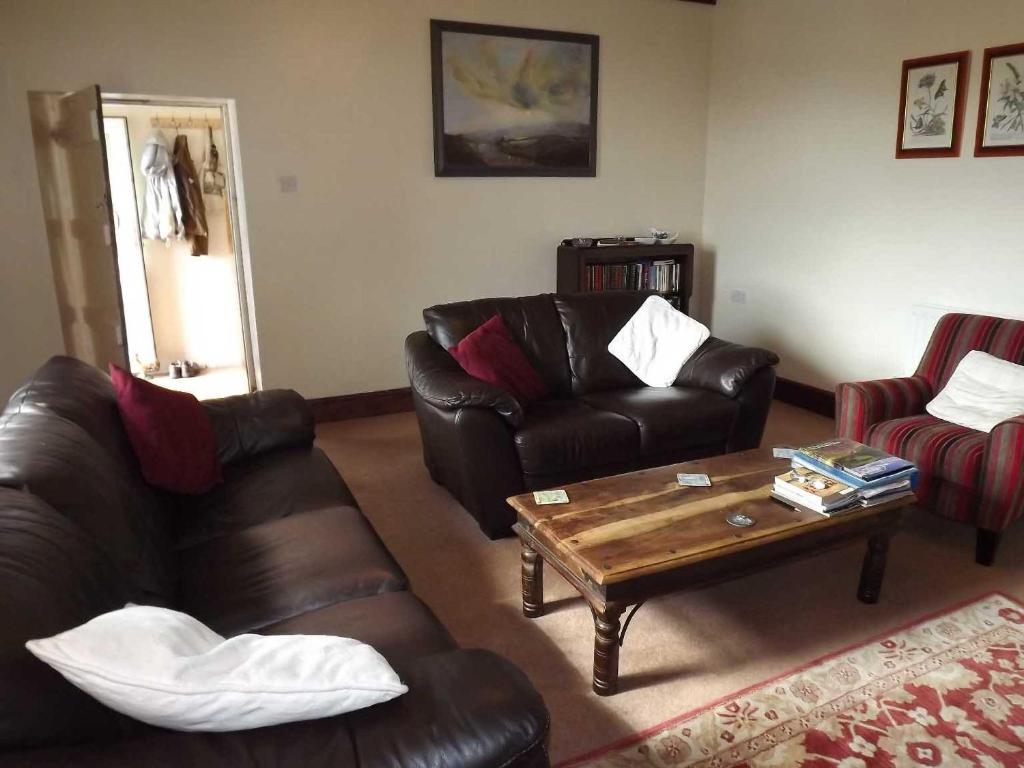 a living room with two leather couches and a coffee table at Skellgill House in Askrigg