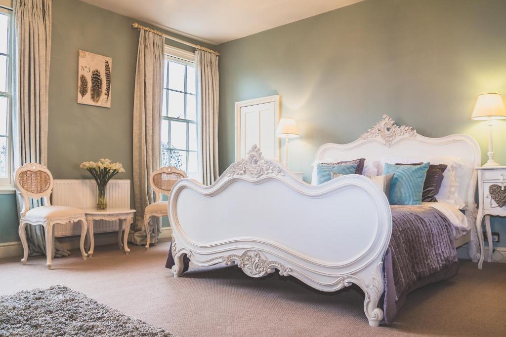 a bedroom with a large white bed and chairs at The Salwey Arms in Ludlow