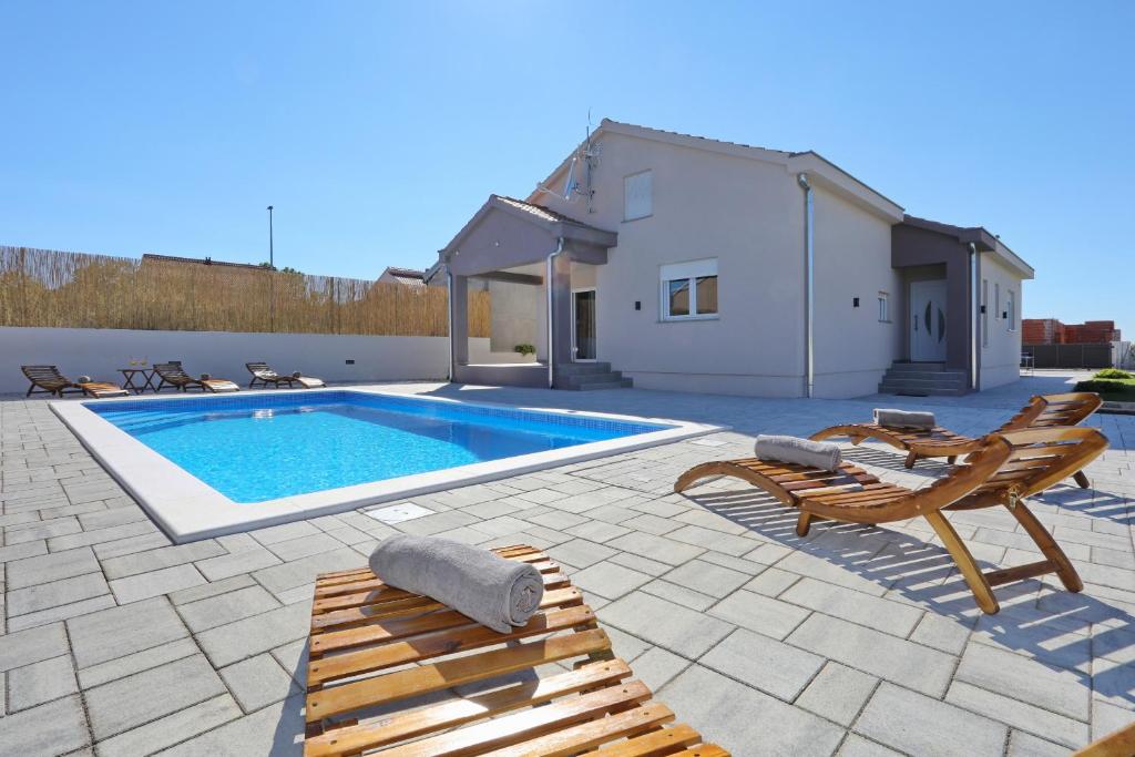 a swimming pool with chairs and a house at Holiday home Fjaka with swimming pool in Pridraga