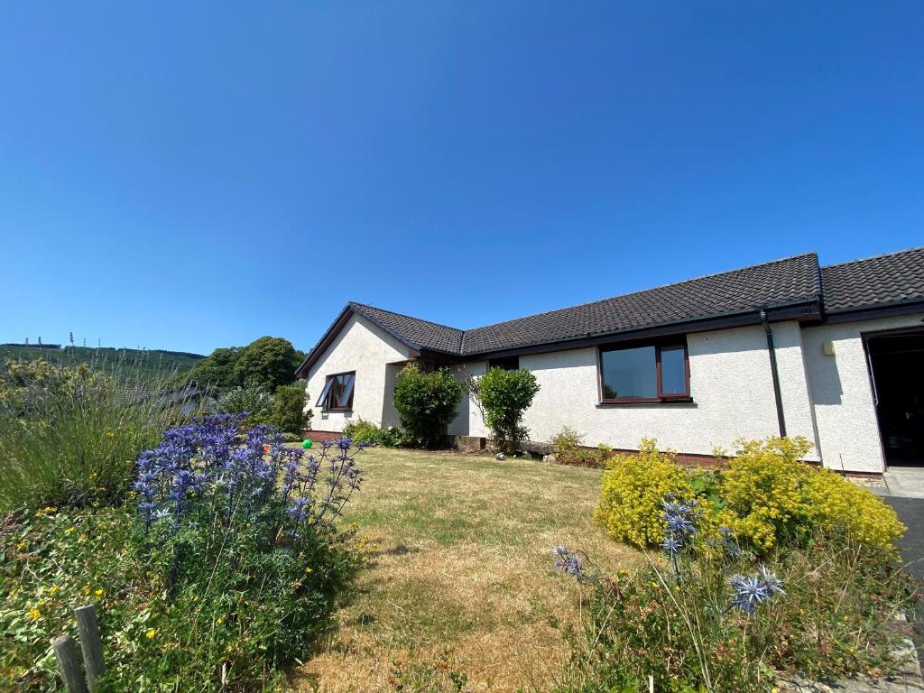 a house with a yard with purple flowers at Seagrass in Lamlash