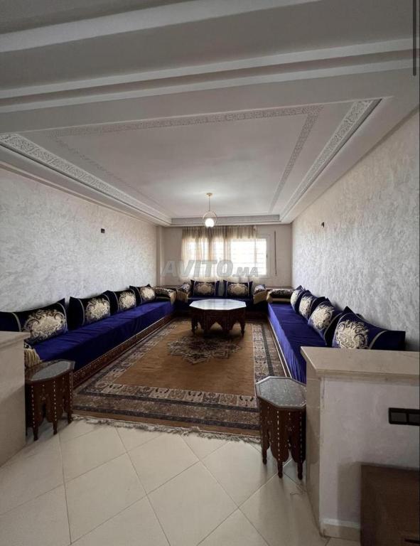 a large living room with blue couches and a table at Appartement Centre Ville in Kenitra
