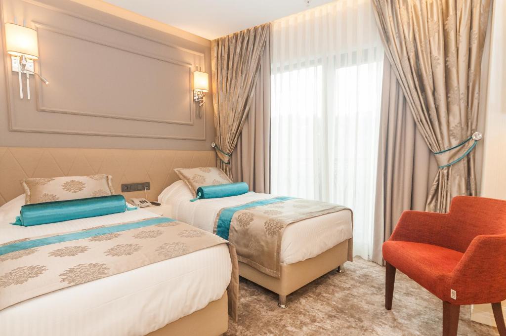 um quarto de hotel com duas camas e uma cadeira em Park Grazza Hotel em Istambul