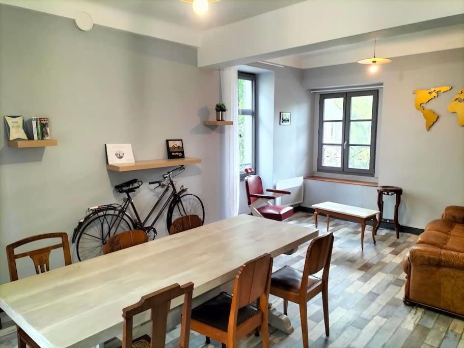 - un salon avec une table, des chaises et un vélo dans l'établissement La maison aux ardoises, à Oloron-Sainte-Marie
