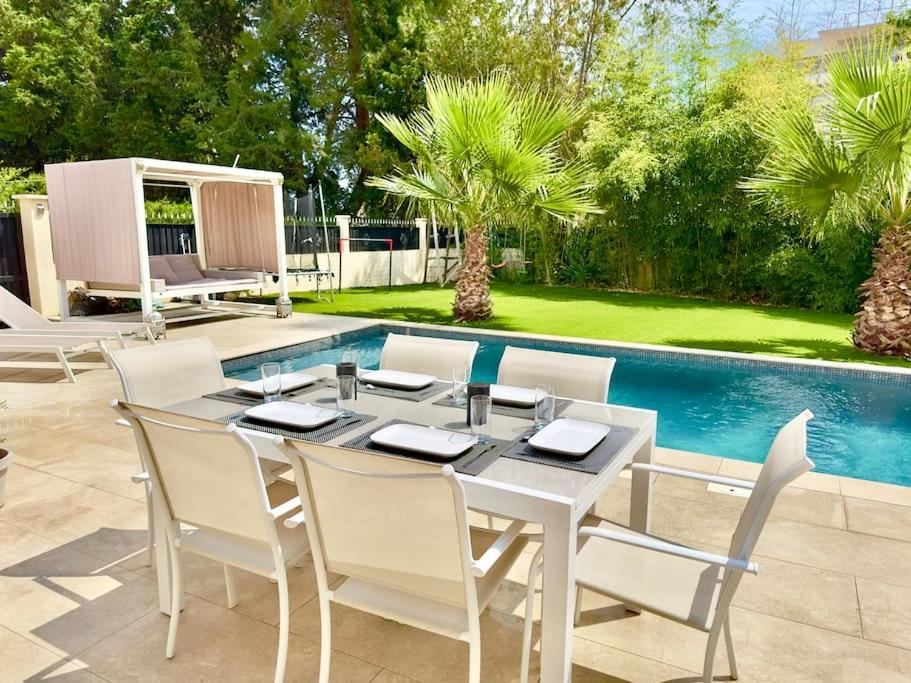 - une table à manger et des chaises blanches à côté de la piscine dans l'établissement Villa avec Piscine Privée à Antibes - Côte d'Azur, à Antibes