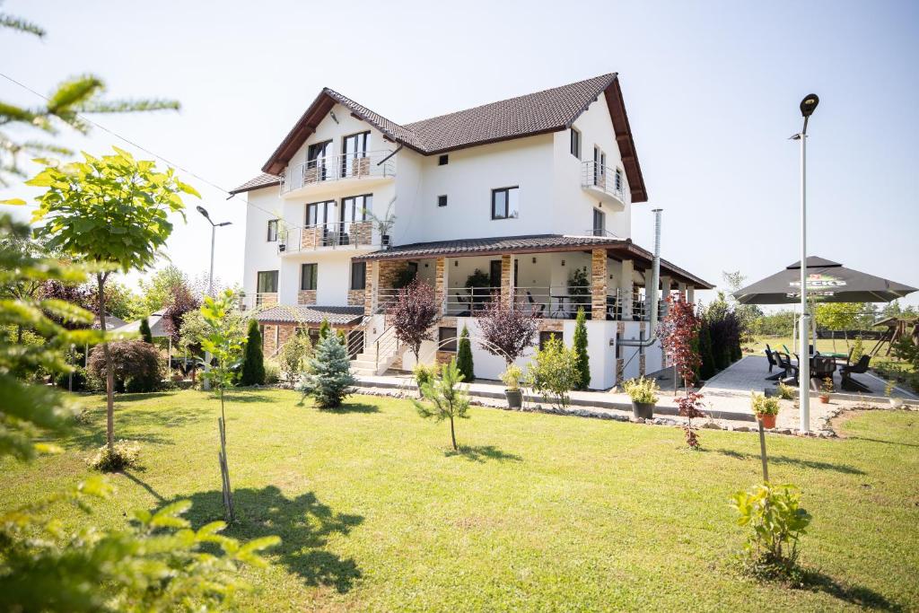 a large white house with a yard with trees at Rem Garden in Novaci