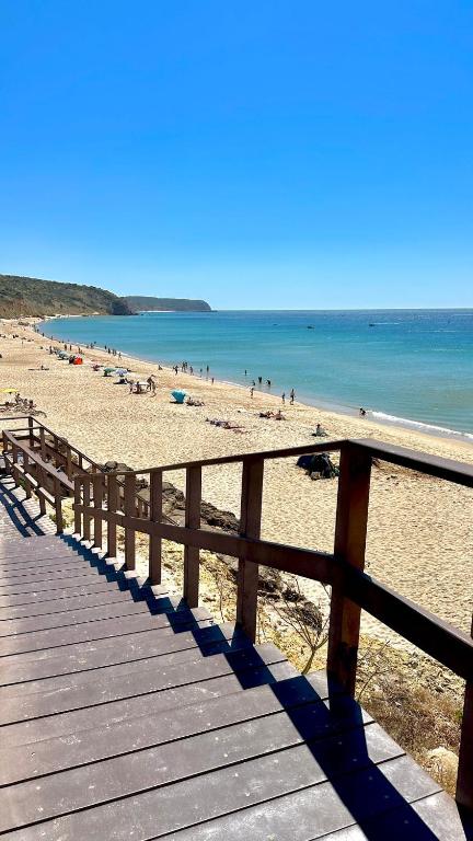 a wooden boardwalk on a beach with people in the water at Casa do Mar in Salema