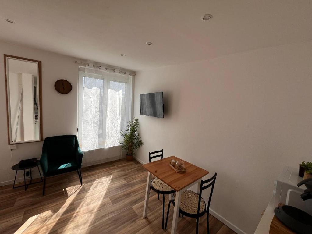 ein Wohnzimmer mit Tisch und Stühlen und einem Fenster in der Unterkunft Studio -La madeleine- proche Gares de Lille in Lille