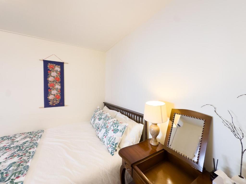 a bedroom with a bed with a mirror and a lamp at Yunseul- Garden House in the City with Korean Beauty in Seoul