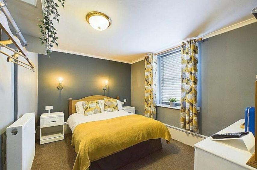 a bedroom with a yellow bed and a window at The Coach House in Beckermet