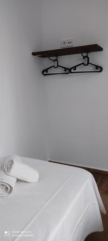 a white bed with a tv on top of it at Apartamentos Bolonia - M a n u e l a in Bolonia
