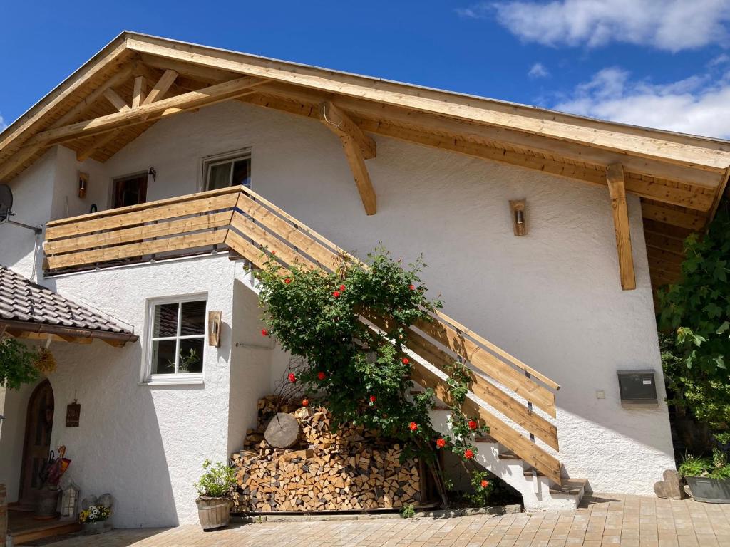 une maison blanche avec un toit en bois et des fleurs dans l'établissement Ferienwohnung / Appartement Bergliebe, à Garmisch-Partenkirchen