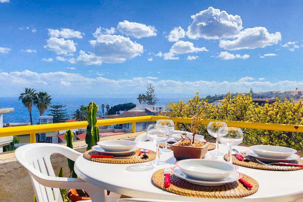 a white table with plates and wine glasses on a balcony at Villa Angelina - Mare Privato in Cannizzaro