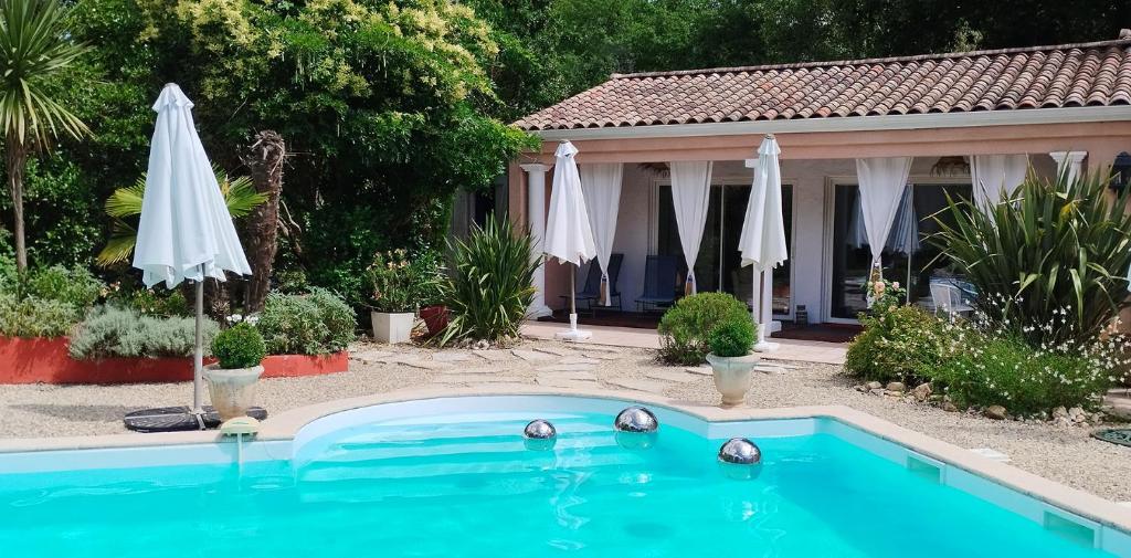- une piscine avec un parasol et une maison dans l'établissement Sur la route des châteaux du Médoc, à Blanquefort