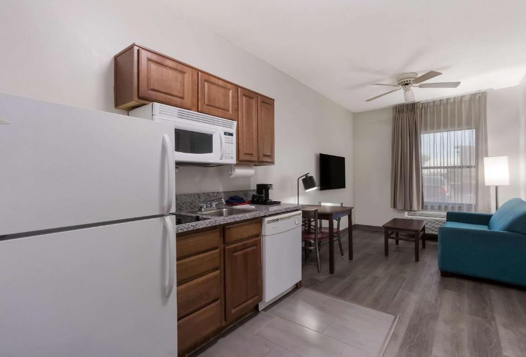 a kitchen with a white refrigerator and a living room at MainStay Suites Extended Stay Hotel Casa Grande in Casa Grande