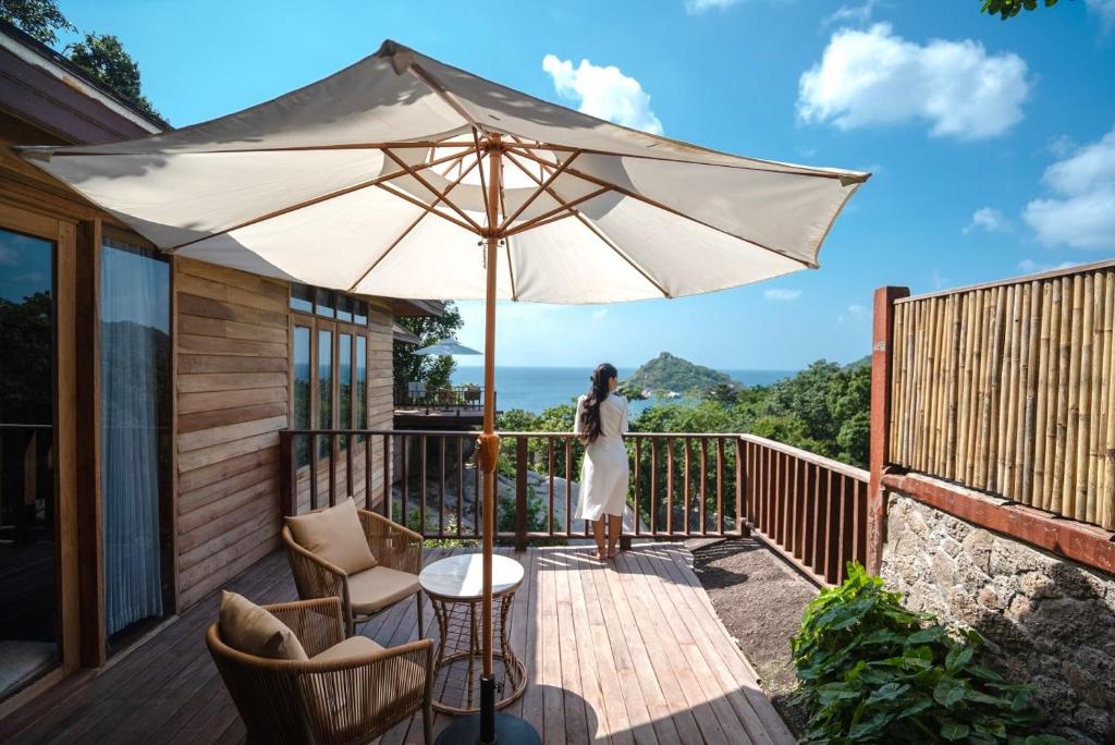 a woman standing on a deck with an umbrella at Dusit Buncha Koh Tao by Riya Group in Ko Tao