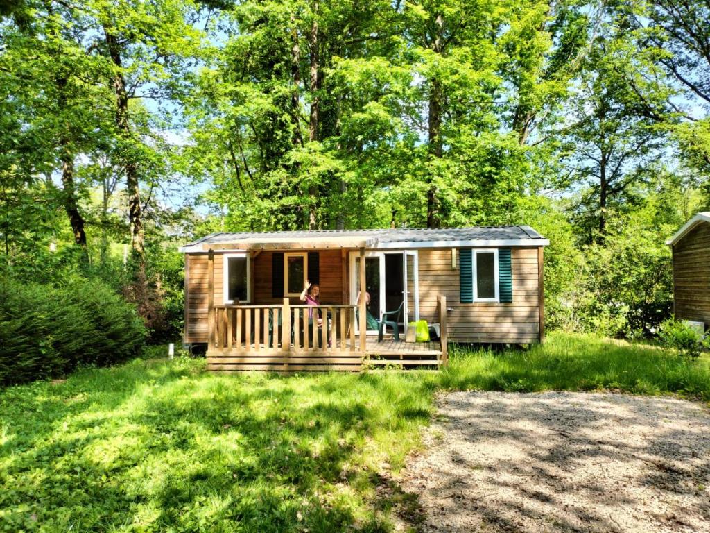 Une femme debout sur la terrasse couverte d'une petite maison dans l'établissement Magnifique mobil-home ensoleillé 6 couchages à une heure de Paris, à Saint-Chéron