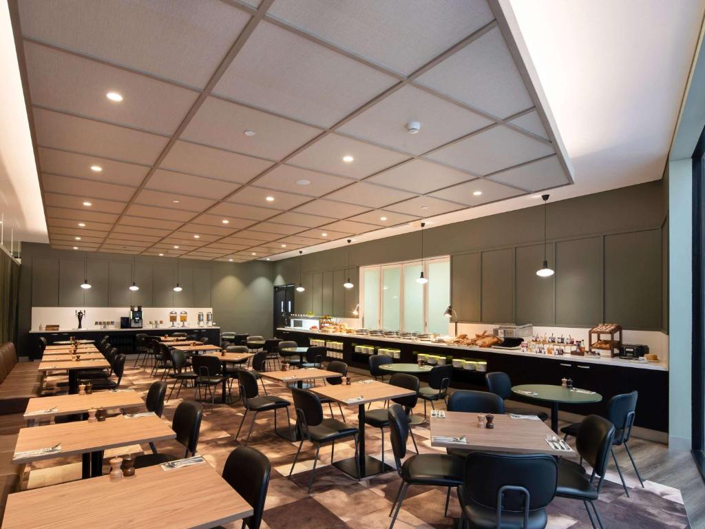 a restaurant with wooden tables and chairs and a kitchen at Mercure Melbourne Southbank in Melbourne