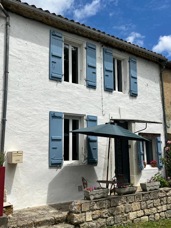 un bâtiment blanc avec des volets bleus et un parapluie dans l'établissement Cute 2 bed cottage - Fources, Gascony, à Fourcès