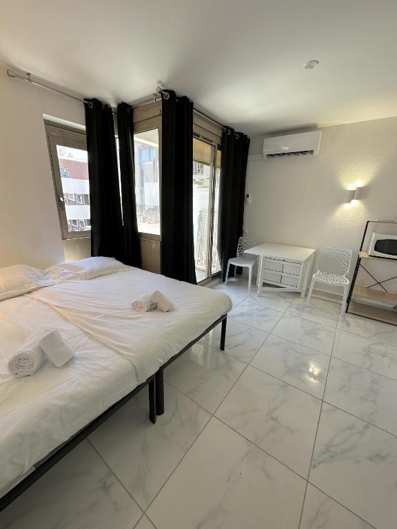 une chambre avec un lit, une table et des fenêtres dans l'établissement Résidence Graziella Studio 604, à Juan-les-Pins