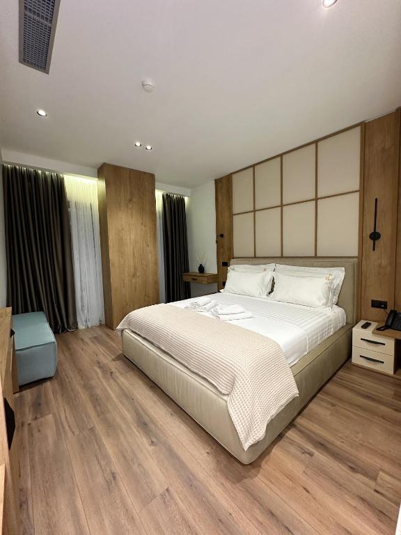 a bedroom with a large white bed and wooden floors at Beliz Boutique Hotel in Vlorë