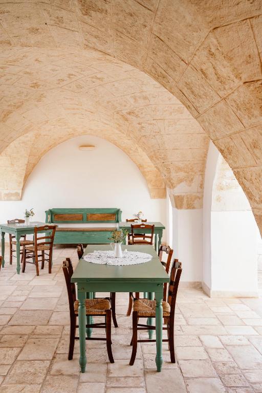 a dining room with green tables and wooden chairs at Masseria Gorgognolo in Ostuni