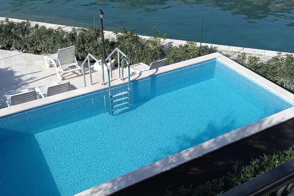 a blue swimming pool with chairs next to the water at Apartment Marija in Risan
