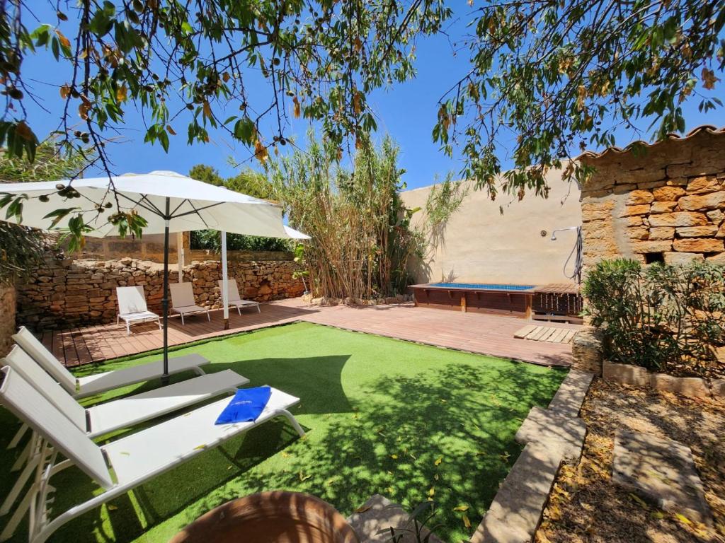 a patio with an umbrella and a lawn at Casa Can Bernat in Santanyi