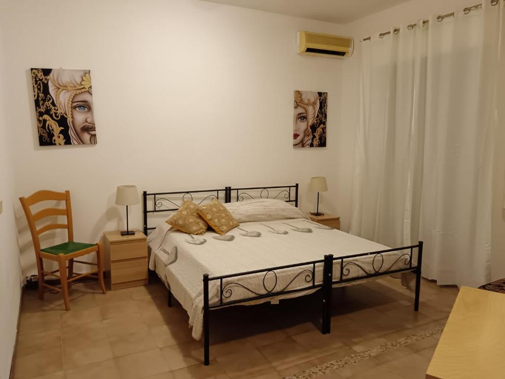 ein Schlafzimmer mit einem Bett und zwei Bildern an der Wand in der Unterkunft San Nicolò House in Aci Catena