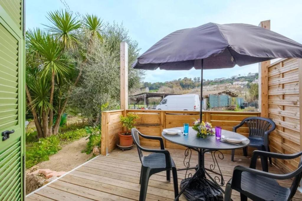 - une table et des chaises sur une terrasse en bois avec un parasol dans l'établissement Appartement moderne à Villeneuve-Loubet, 45 m², terrasse aménagée, à Villeneuve-Loubet