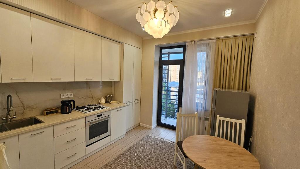 a kitchen with white cabinets and a table and a window at City Park Apartments in Osh