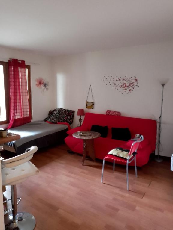 un salon avec un canapé rouge et une table dans l'établissement Grand Studio Gentilly, à Gentilly