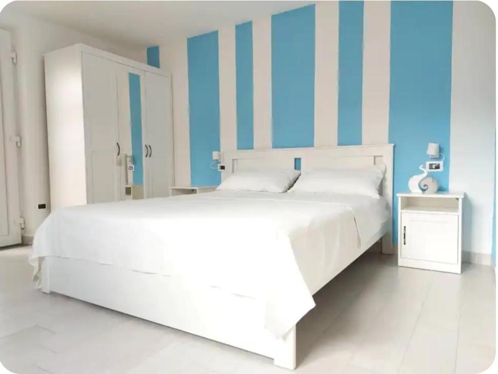 a white bed in a room with blue and white stripes at Il Leccio in Ischia