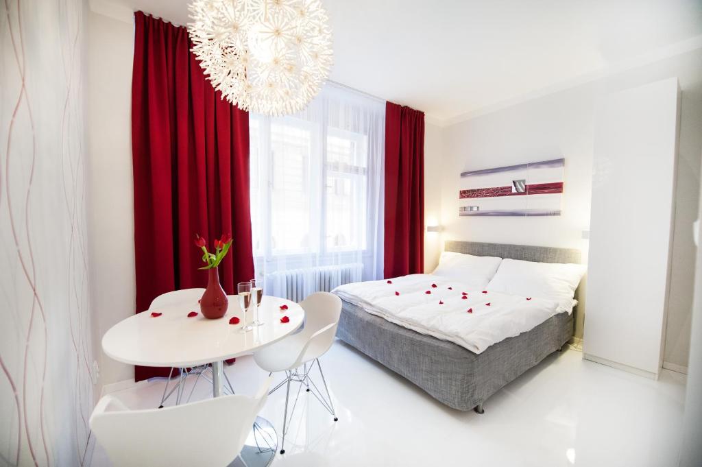 um quarto com uma cama e uma mesa e cadeiras brancas em Honeymoon Ruterra studio em Praga