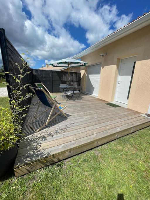 une terrasse en bois avec une chaise et un parasol dans l'établissement Le Porge location T2 neuf, à Le Porge