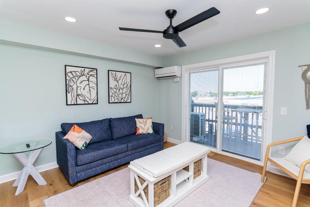 a living room with a blue couch and a balcony at 127th Street OCMD Condo in Ocean City