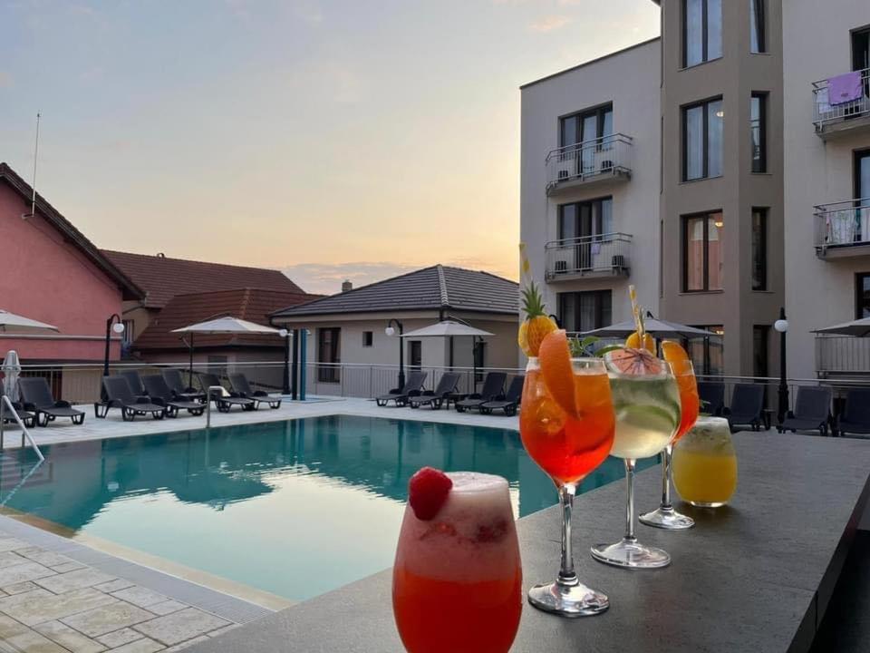 a group of drinks on a table next to a swimming pool at Pensiunea Tulip in Baile Felix