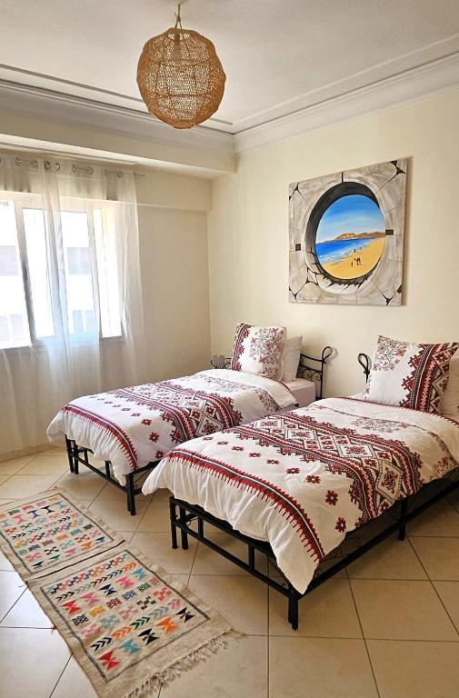 a bedroom with two beds and a painting on the wall at Plein centre, plage & souks à deux pas ! in Agadir