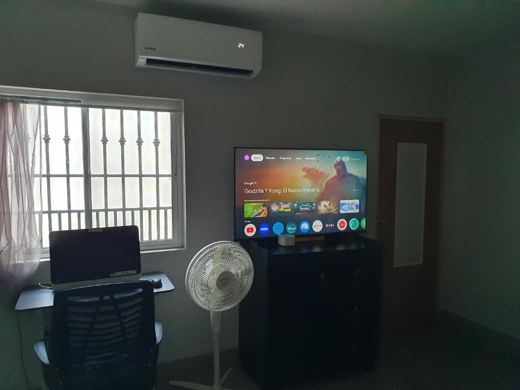 a living room with a flat screen tv and a fan at Habitacion Matrimonial in Monterrey