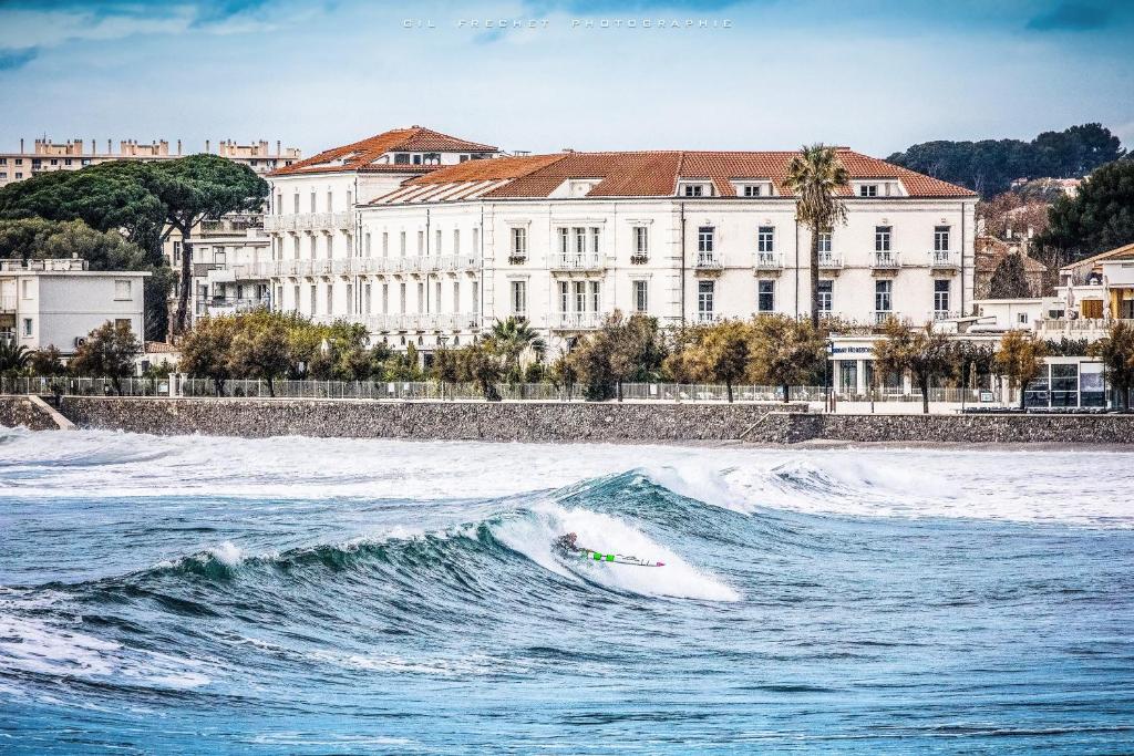 un surfeur fait une vague dans l'océan dans l'établissement Grand Hotel Des Sablettes Plage, Curio Collection By Hilton, à La Seyne-sur-Mer