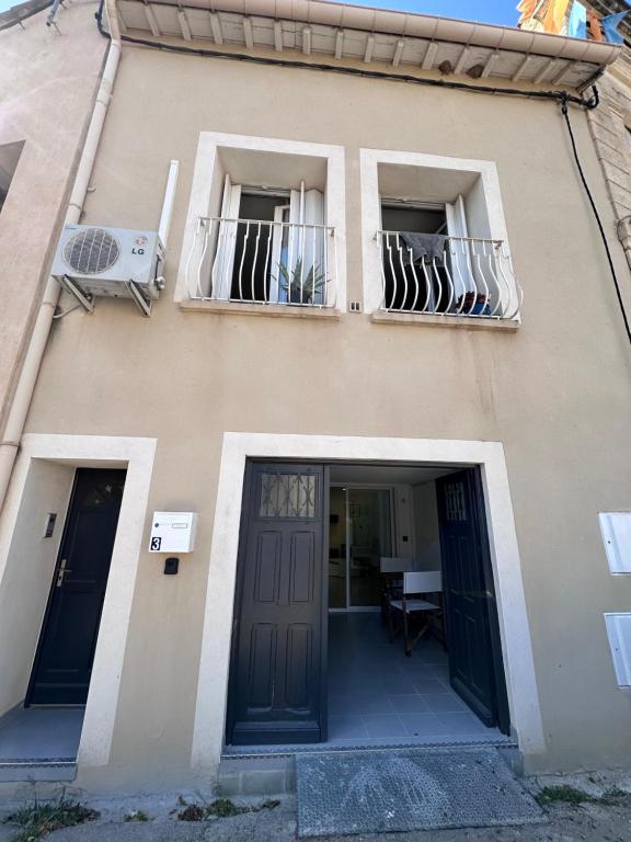 - un bâtiment avec deux fenêtres, une porte et un balcon dans l'établissement Studio en coeur de village, à Frontignan